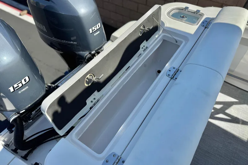 Slide: The Image of 2022 Robalo R247 Dual Console boat with Yamaha 150 engines and open storage compartment. - 30