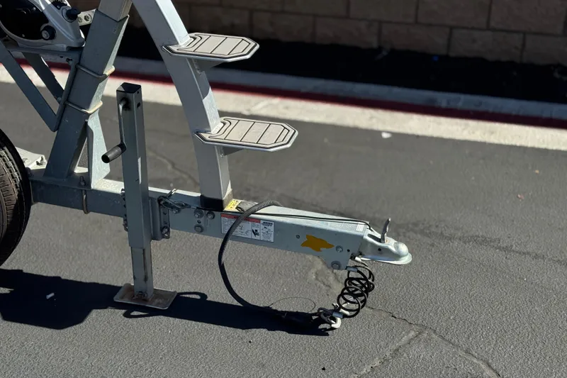 Slide: The Image of Trailer hitch and steps of a 2022 Robalo R247 Dual Console boat on pavement. - 48