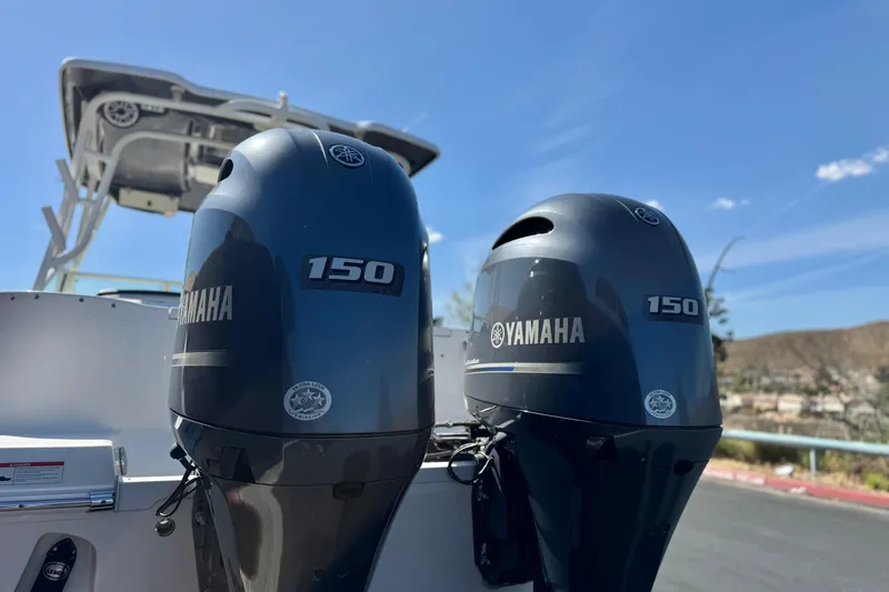 Slide: The Image of Twin Yamaha 150 engines on a 2022 Robalo R247 Dual Console boat under clear skies. - 7