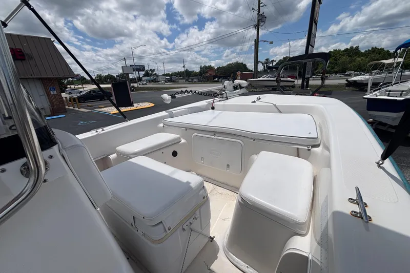 Slide: The Image of 2008 Sundance B18CC boat interior with white seating and storage compartments under a cloudy sky. - 12