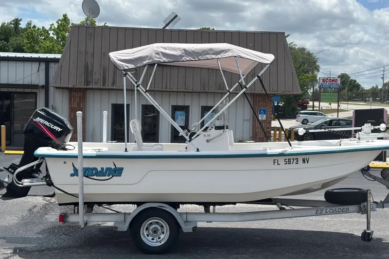 Slide: The Image of 2008 Sundance B18CC boat on trailer with Mercury outboard motor, parked outside a building. - 5