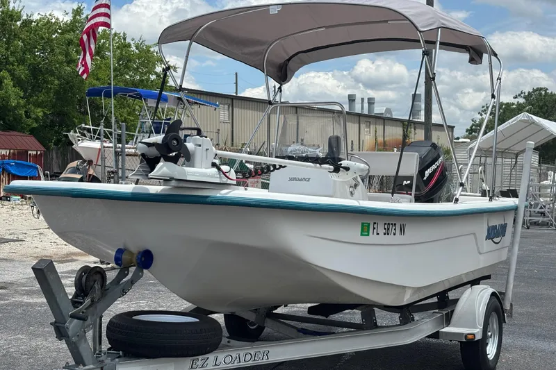 Slide: The Image of 2008 Sundance B18CC boat on trailer with canopy, parked outdoors under cloudy sky. - 8