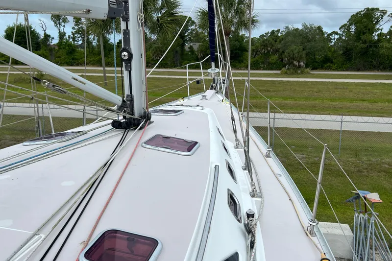 Slide: The Image of 2008 Catalina 470 sailboat deck with rigging and hatches, surrounded by greenery. - 13
