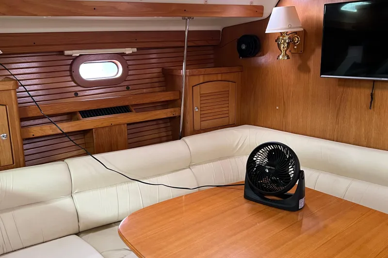 Slide: The Image of Interior of 2008 Catalina 470 yacht with wooden paneling, white seating, and a small fan on the table. - 19