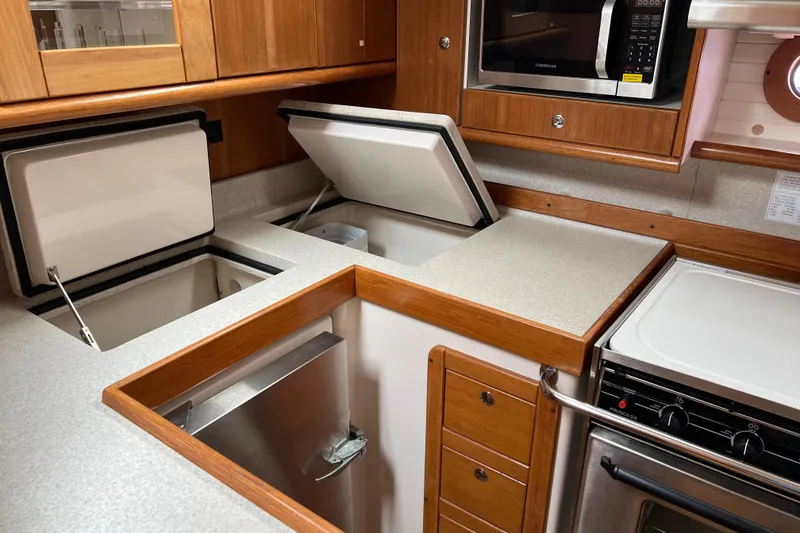 Slide: The Image of 2008 Catalina 470 yacht kitchen with open storage compartments and modern appliances. - 25