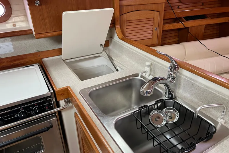 Slide: The Image of Galley kitchen in 2008 Catalina 470 yacht with sink, stove, and wooden cabinetry. - 26