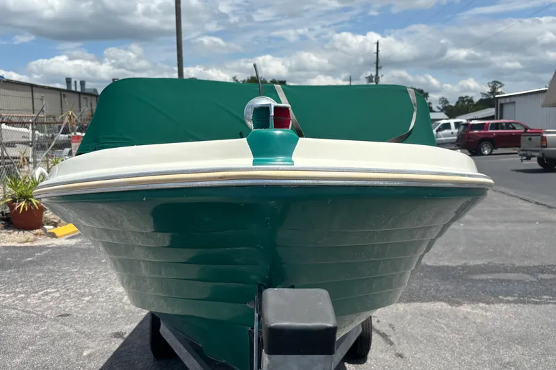 Slide: The Image of 1966 Mohawk 15 boat with green cover, parked outdoors under a cloudy sky. - 14