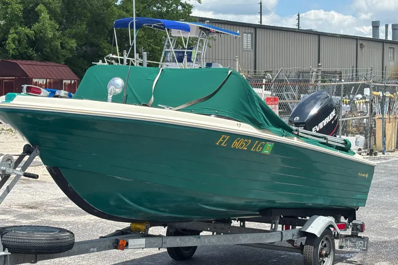 Slide: The Image of 1966 Mohawk 15 boat on trailer with green cover and Evinrude motor. - 15