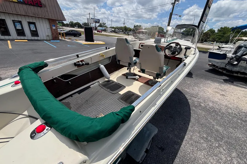 Slide: The Image of 1966 Mohawk 15 boat with green trim, parked outdoors under a cloudy sky. - 16
