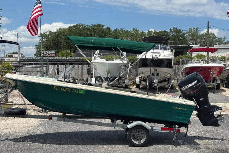 Slide: The Image of 1966 Mohawk 15 boat with green canopy on trailer, parked near other boats. - 2