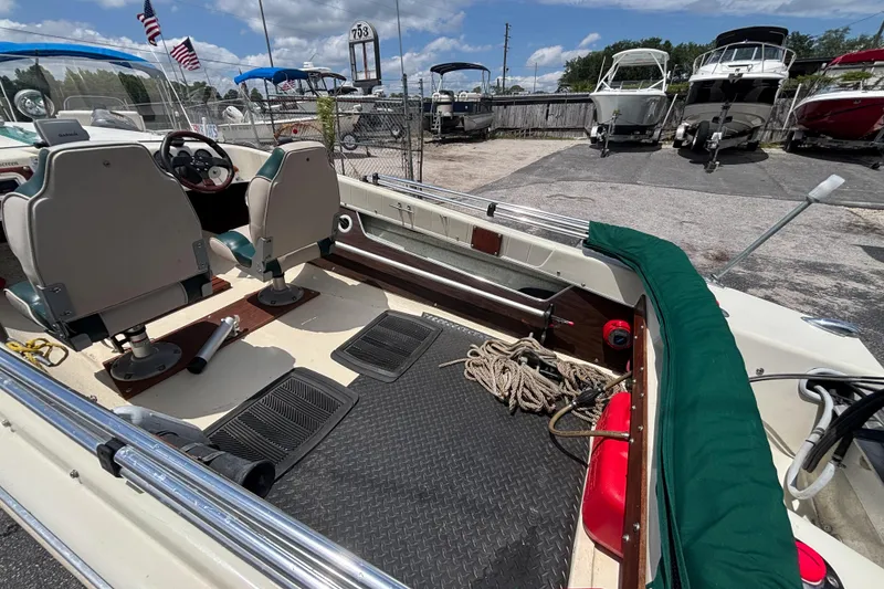 Slide: The Image of 1966 Mohawk 15 boat interior with seats, steering wheel, and ropes, docked near other boats. - 21