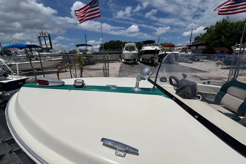 Slide: The Image of 1966 Mohawk 15 boat with American flags, parked in a marina under a blue sky. - 23