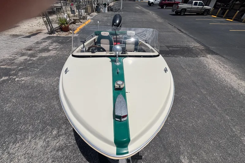 Slide: The Image of 1966 Mohawk 15 boat with green stripe, parked on asphalt, featuring windshield and steering wheel. - 24