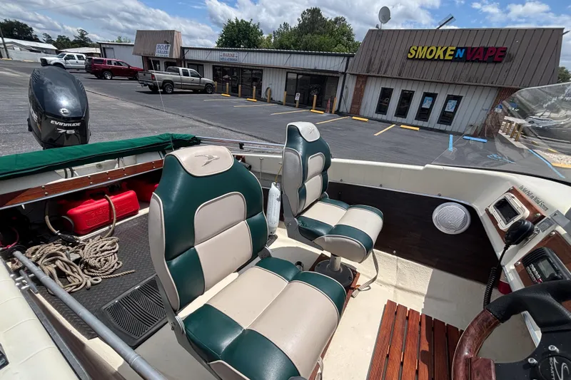 Slide: The Image of Interior of a 1966 Mohawk 15 boat with green and white seats, parked near a store. - 25