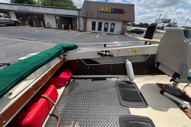 Slide: The Image of 1966 Mohawk 15 boat interior with red fuel tanks, parked near a smoke shop. - 28
