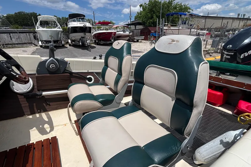Slide: The Image of 1966 Mohawk 15 boat interior with green and white seats, steering wheel, and docked boats in background. - 34