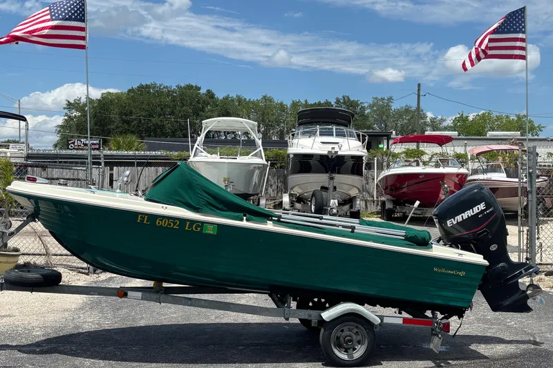 Slide: The Image of 1966 Mohawk 15 boat on trailer, green hull, Evinrude motor, American flags in background. - 4
