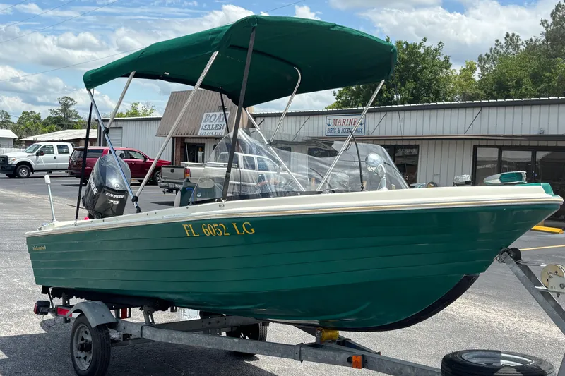 Slide: The Image of 1966 Mohawk 15 boat with green hull on trailer, parked outside marine store. - 7