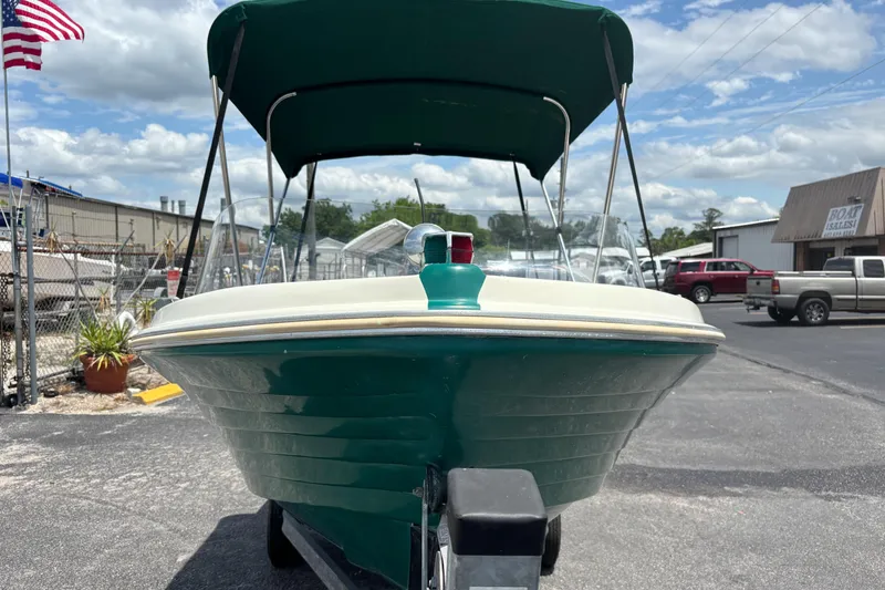 Slide: The Image of 1966 Mohawk 15 boat with green hull and canopy, parked outdoors under a cloudy sky. - 8