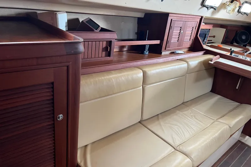 Slide: The Image of Main salon 2002 Island Packet 380 sailboat with beige leather seating and wooden cabinetry. - 16