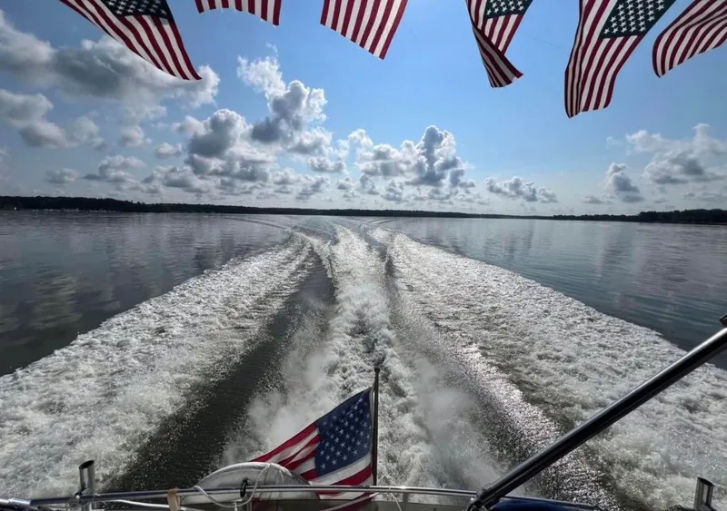 Slide: The Image of 1988 Chris-Craft 381 Catalina cruising on calm waters with American flags. - 18