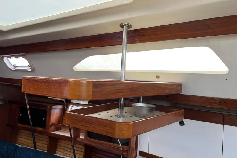 Slide: The Image of Interior of a 1997 Catalina 400 sailboat featuring wooden cabinetry and a mounted table. - 12