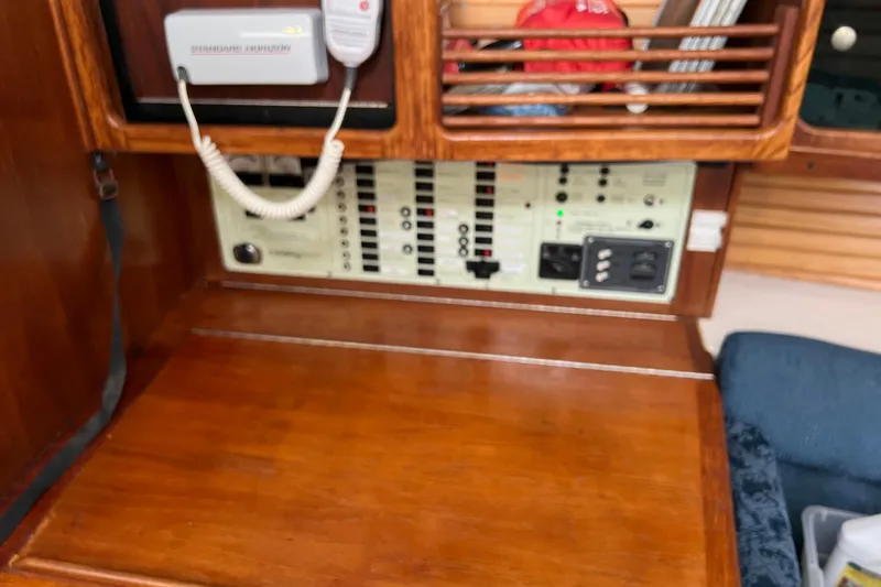 Slide: The Image of Control panel inside a 1997 Catalina 400 sailboat, featuring wooden cabinetry and communication equipment. - 19