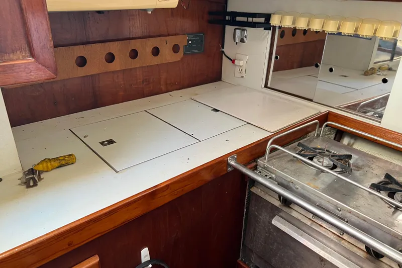 Slide: The Image of 1977 Gulfstar 43 yacht kitchen with stove, wooden cabinetry, and countertop storage. - 11