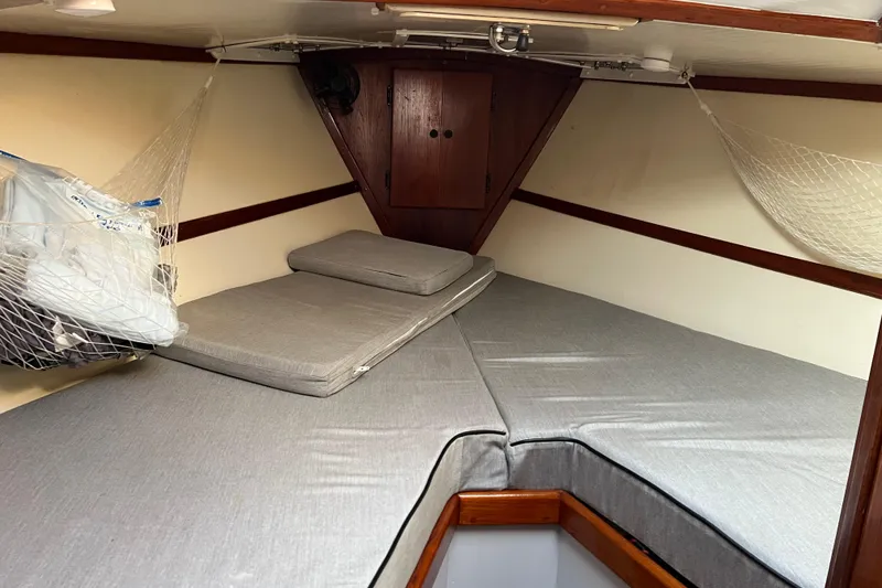 Slide: The Image of 1977 Gulfstar 43 sailboat cabin with gray cushions and storage nets. - 12