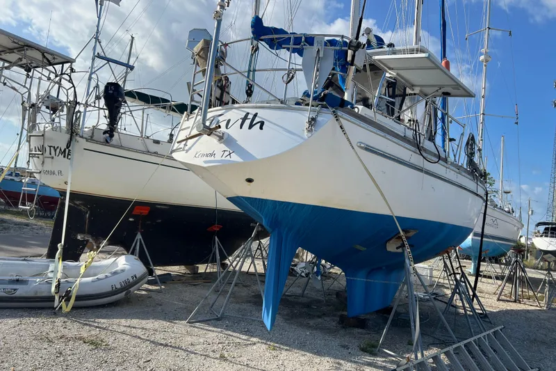 Slide: The Image of 1977 Gulfstar 43 sailboat on stands, blue hull, in a boatyard under a clear sky. - 3