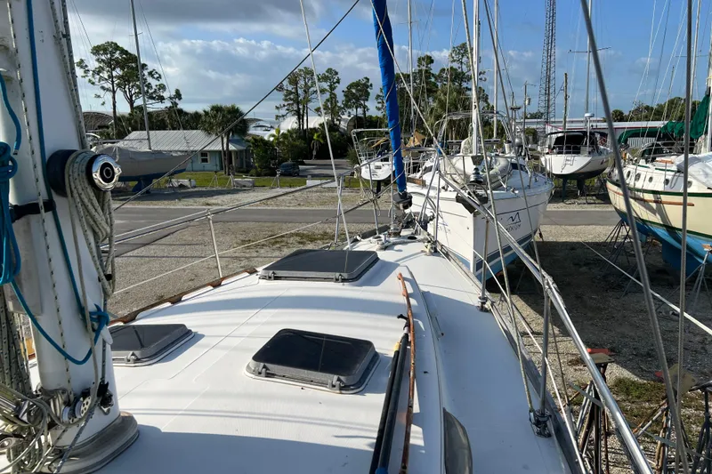 Slide: The Image of 1977 Gulfstar 43 sailboat on land, surrounded by other boats, under a clear sky. - 4