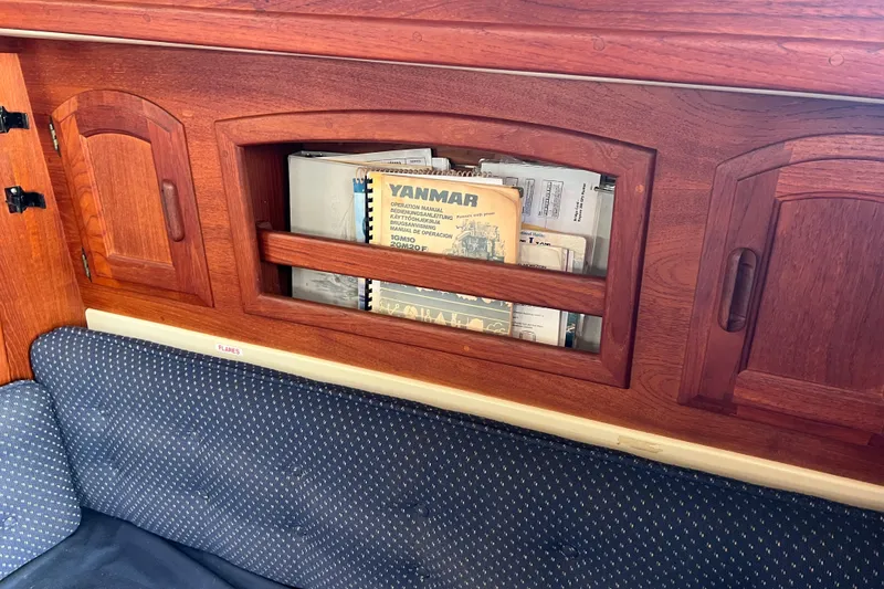 Slide: The Image of Wooden cabinet with manuals inside a 1989 Pacific Seacraft Dana 24 sailboat interior. - 10