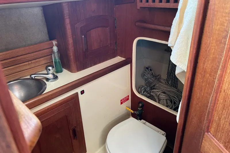 Slide: The Image of 1989 Pacific Seacraft Dana 24 boat interior with wooden cabinetry and compact bathroom. - 12