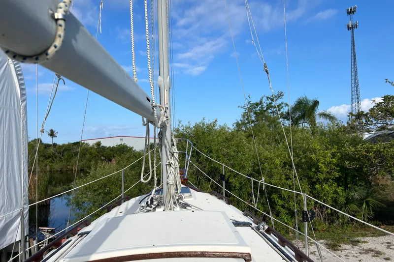 Slide: The Image of 1989 Pacific Seacraft Dana 24 sailboat docked near lush greenery under a clear blue sky. - 4