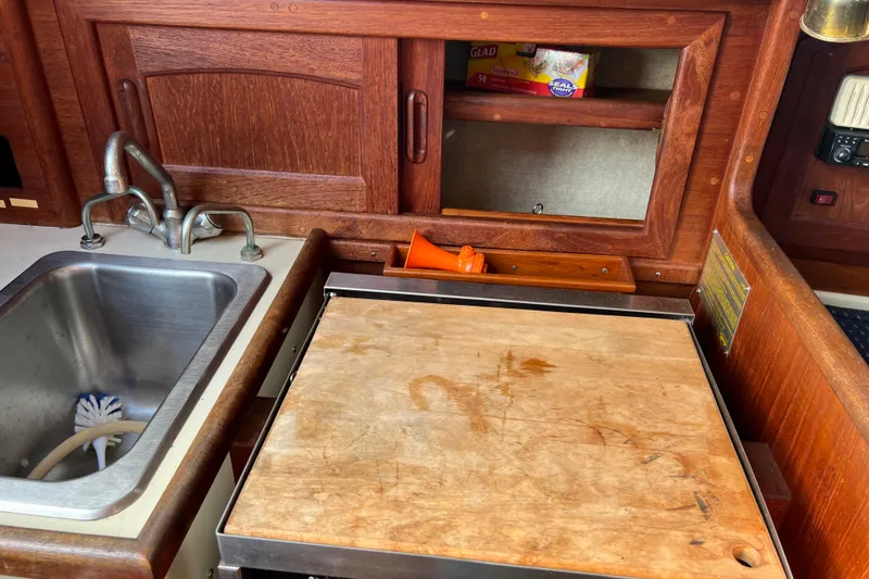 Slide: The Image of 1989 Pacific Seacraft Dana 24 galley with sink, cutting board, and storage cabinet. - 8