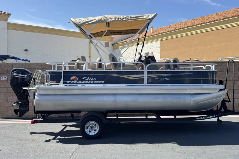 The Image of 2024 Sun Tracker Bass Buggy 18 DLX pontoon boat on trailer, parked outdoors. - 0