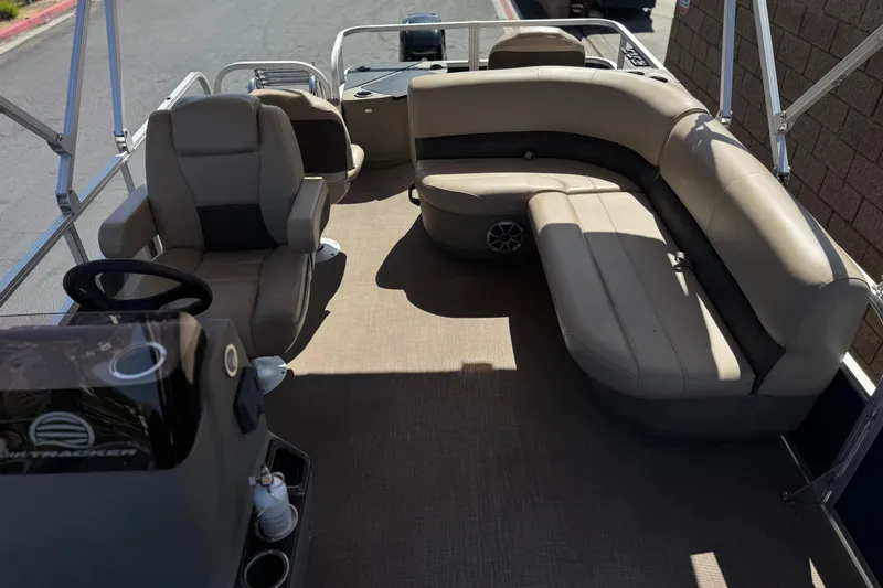 Slide: The Image of 2024 Sun Tracker Bass Buggy 18 DLX pontoon boat interior with beige seating and steering console. - 16