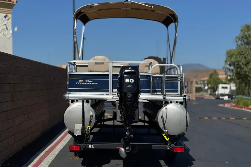 Slide: The Image of 2024 Sun Tracker Bass Buggy 18 DLX pontoon boat with Mercury 60 engine, parked outdoors. - 5