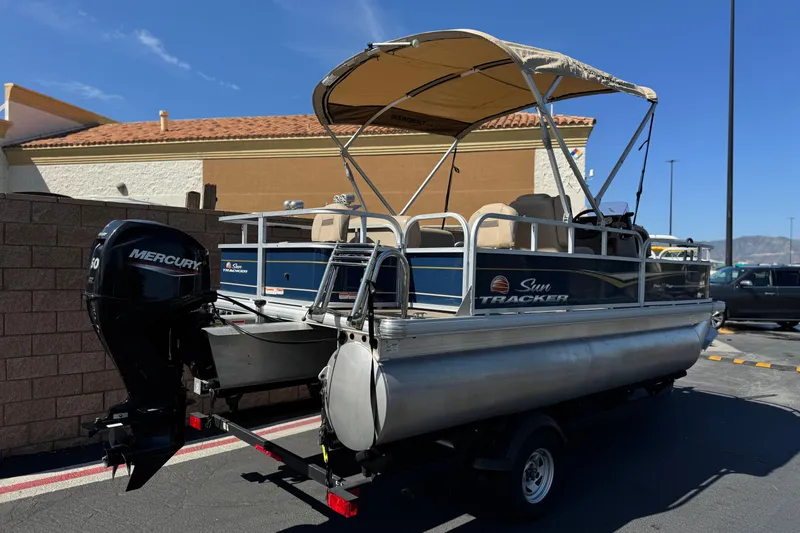 Slide: The Image of 2024 Sun Tracker Bass Buggy 18 DLX pontoon boat with Mercury engine, parked outdoors. - 6