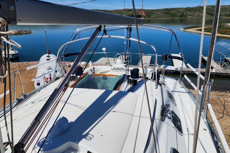 Slide: The Image of 1997 Beneteau First 36s7 sailboat docked by a serene lake with clear blue skies. - 12