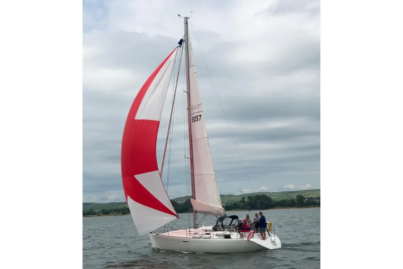Slide: The Image of 1997 Beneteau First 36s7 sailboat with red and white spinnaker on open water. - 2