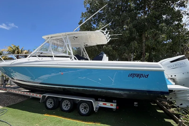 The Image of 2006 Intrepid 348 Walkaround boat on trailer, blue hull, Suzuki engines, sunny day. - 1
