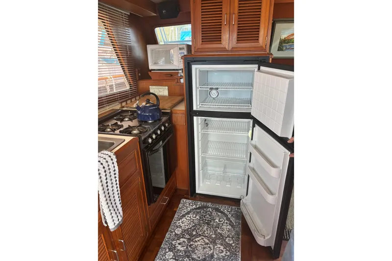 Slide: The Image of 1984 Ocean Alexander 38 Double Cabin kitchen with stove, open fridge, and wooden cabinetry. - 11