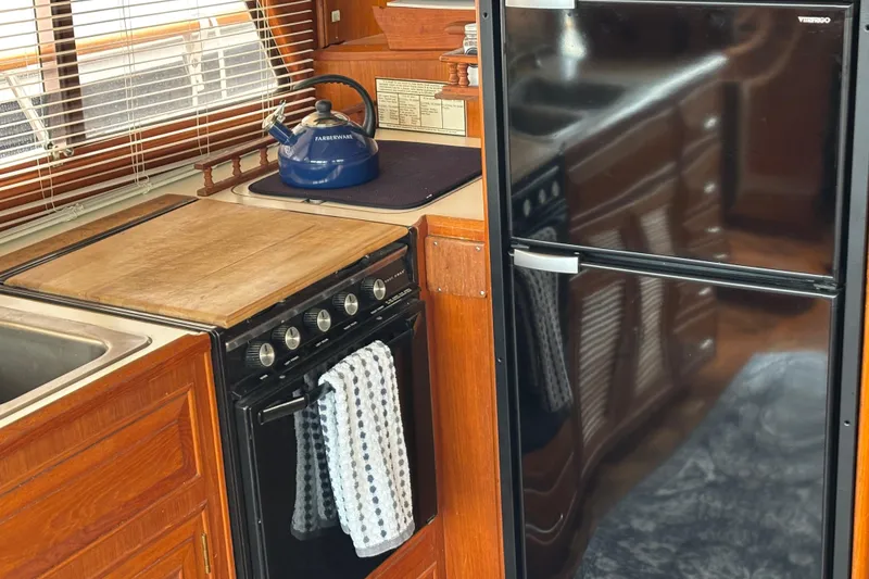 Slide: The Image of 1984 Ocean Alexander 38 Double Cabin kitchen with stove, fridge, and wooden cabinetry. - 9