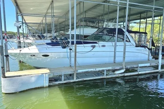 Slide: The Image of 2001 Sea Ray 380 Sundancer docked in a marina, sheltered under a covered slip. - 2