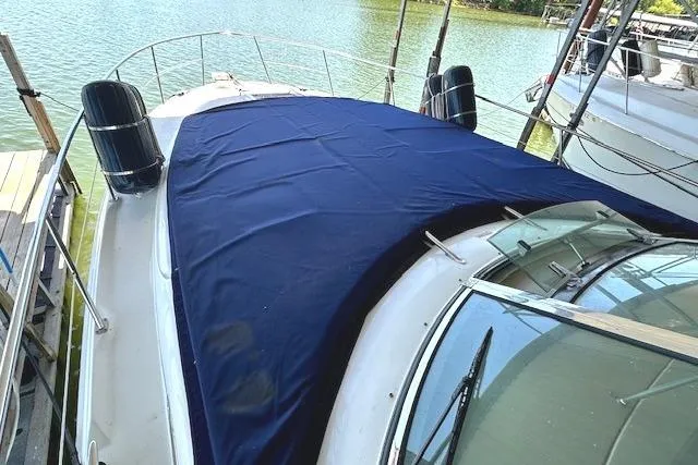 Slide: The Image of 2001 Sea Ray 380 Sundancer yacht with blue cover docked by the water. - 26