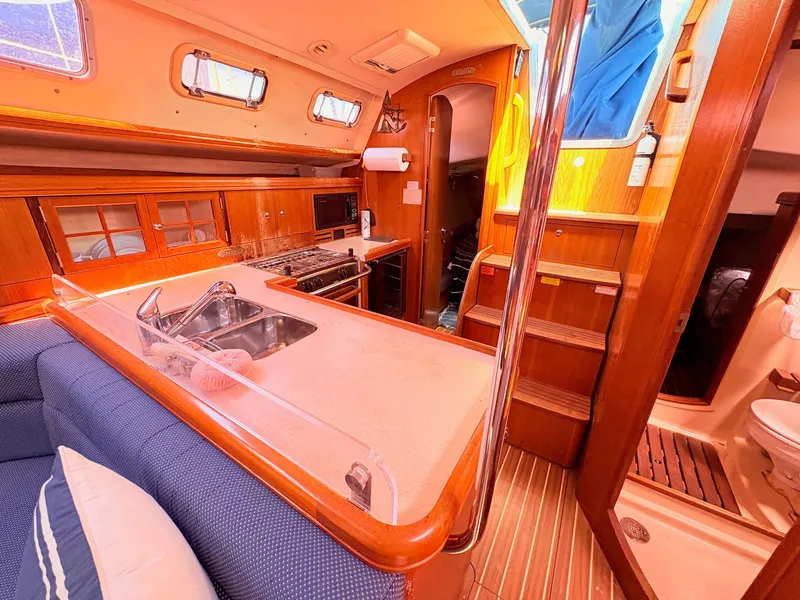 Slide: The Image of Interior of a 2006 Hunter 38 yacht featuring kitchen and seating area. - 12