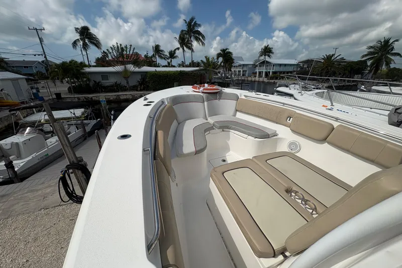 Slide: The Image of 2017 Sea Fox 288 Commander boat interior with seating, docked near palm trees and houses. - 10