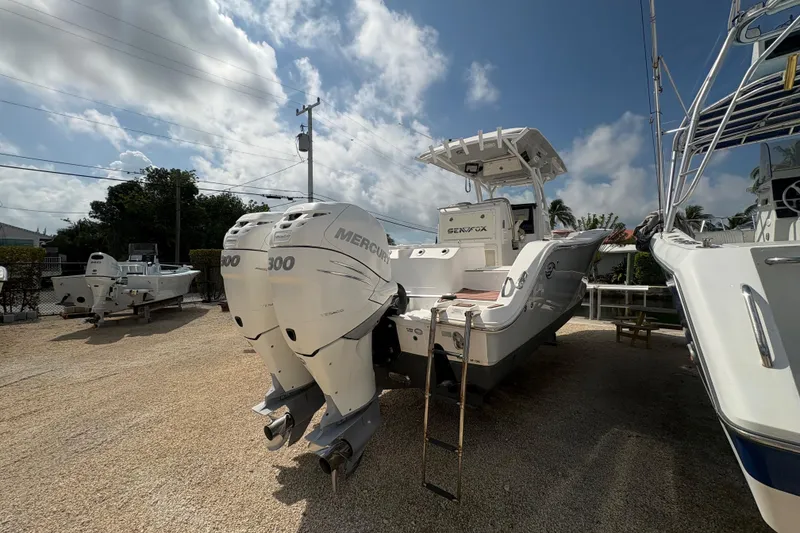 Slide: The Image of 2017 Sea Fox 288 Commander boat with twin Mercury 300 engines, parked outdoors. - 8