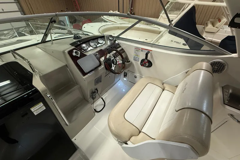 Slide: The Image of 2012 Sea Ray Sundancer 280 cockpit with steering wheel, gauges, and beige seating. - 25